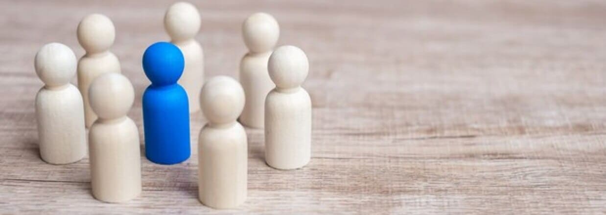 Sette birilli bianchi che circondano un birillo blu posto al centro